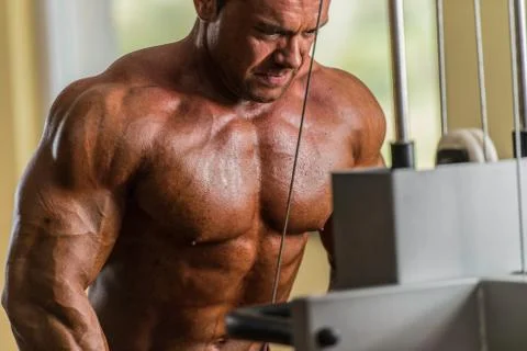 Bodybuilder doing heavy weight exercise for triceps with cable Stock Photos