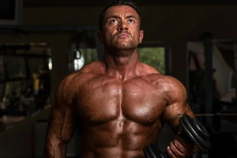Bodybuilder doing heavy weight exercise for biceps with dumbbell Stock Photos