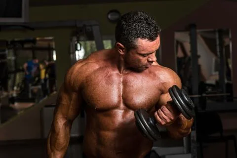 Bodybuilder doing heavy weight exercise for biceps with dumbbell Stock Photos