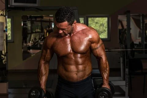 Bodybuilder doing heavy weight exercise for biceps with dumbbell Stock Photos