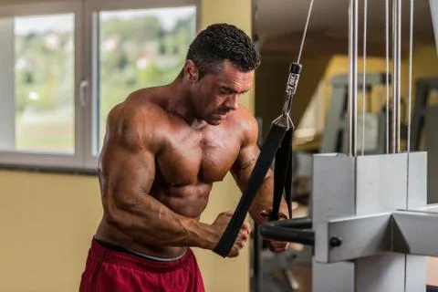 Bodybuilder doing heavy weight exercise for triceps with cable Stock Photos