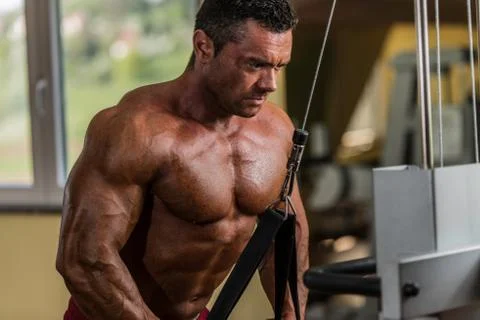 Bodybuilder doing heavy weight exercise for triceps with cable Stock Photos