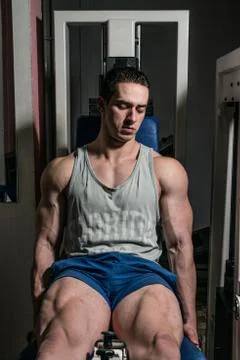 Bodybuilder doing heavy weight exercise for legs on machine leg extensions Stock Photos