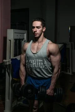 Bodybuilder doing heavy weight exercise for shoulder white dumbbell Stock Photos