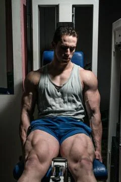 Bodybuilder doing heavy weight exercise for legs on machine leg extensions Stock Photos