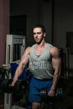 Bodybuilder doing heavy weight exercise for shoulder white dumbbell Stock Photos