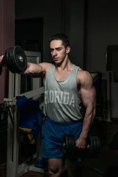 Bodybuilder doing heavy weight exercise for shoulder white dumbbell Stock Photos