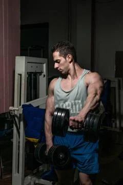 Bodybuilder doing heavy weight exercise for shoulder white dumbbell Stock Photos