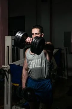 Bodybuilder doing heavy weight exercise for shoulder white dumbbell Stock Photos