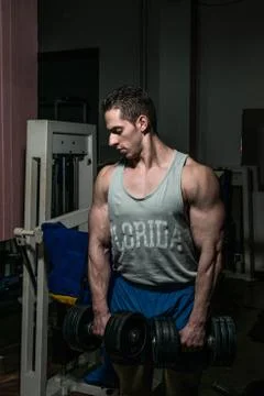 Bodybuilder doing heavy weight exercise for shoulder white dumbbell Stock Photos