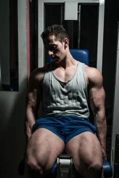 Bodybuilder doing heavy weight exercise for legs on machine leg extensions Stock Photos