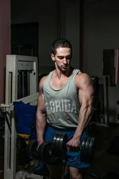 Bodybuilder doing heavy weight exercise for shoulder white dumbbell Stock Photos