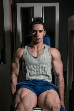 Bodybuilder doing heavy weight exercise for legs on machine leg extensions Stock Photos