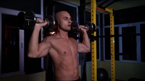 Bodybuilder doing overhead press with dumbbells in a sports club Stock Footage 149495442