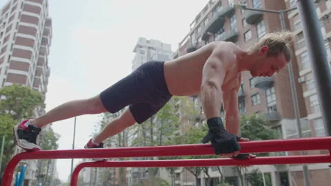 Bodybuilder Doing Push-Ups on Parallel Bars during Street Workout Stock Footage 260047973