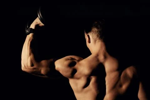 Bodybuilder with dumbbells on a dark background. Stock Photos
