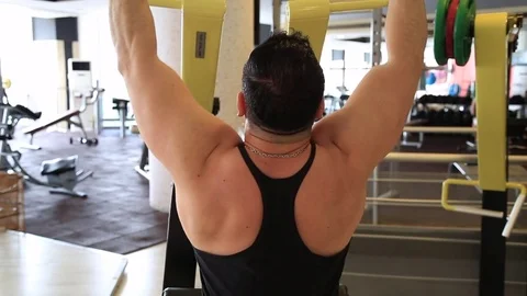 Bodybuilder execute back muscle exercises on pulldown bar machine in gym Stock Footage 76059632