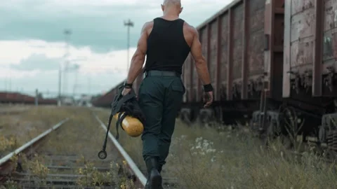 Bodybuilder goes along the rail keeping the balance past freight train and Stock Footage 218401821