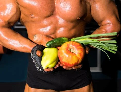 Bodybuilder holding vegetables 库存照片