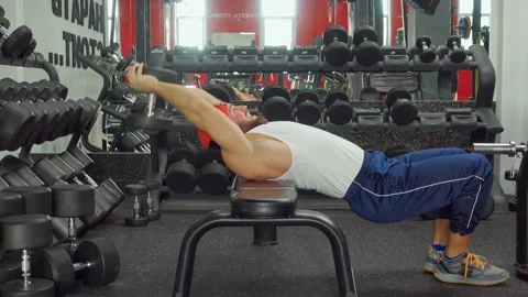 Bodybuilder holds dumbbell and pulls hands behind head, pumping up the triceps 動画素材 188015086