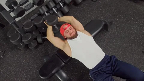 Bodybuilder holds dumbbell and pulls hands behind head, pumping up the triceps Video stock 189954328