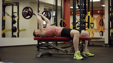Bodybuilder lifting the barbell up and down above his head on bench in gym Stock Footage 97594012
