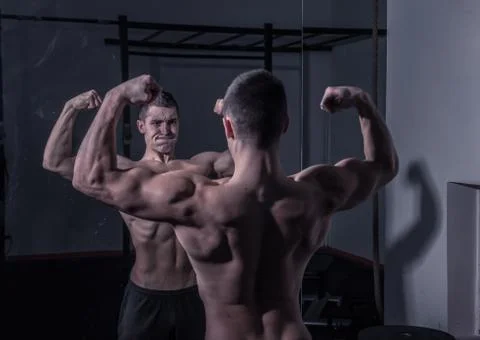 Bodybuilder, looking at himself in mirror, strong muscular Stock Photos