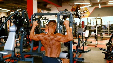 Bodybuilder man hard training muscles at training machine. Stock Footage 81484480