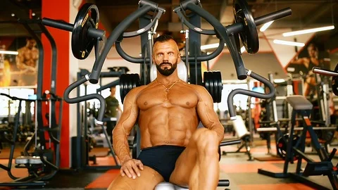 Bodybuilder man hard training muscles at training machine. Stock Footage 81487386