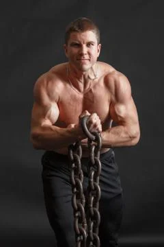 A bodybuilder man posing with iron chain in his hands Stock Photos