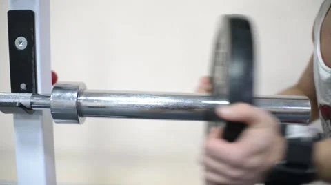 Bodybuilder man puts weight plates on the barbell in the gym Stock Footage 57243299