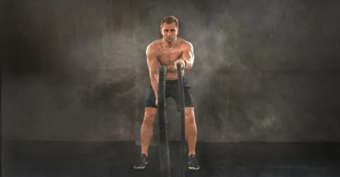 Bodybuilder man workout and exercise with rope in gym and fitness club Stock Photos
