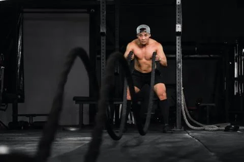 Bodybuilder man workout and exercise with rope in gym and fitness club Stock Photos
