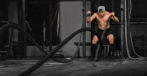 Bodybuilder man workout and exercise with rope in gym and fitness club Stock Photos