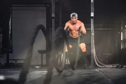 Bodybuilder man workout and exercise with rope in gym and fitness club Stock Photos