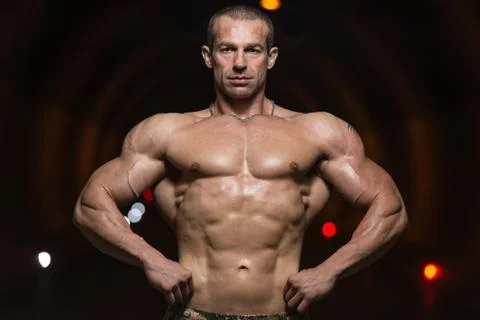Bodybuilder performing front lat spread poses in tunnel Stock Photos