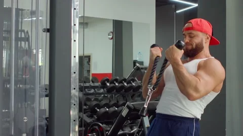 Bodybuilder performs exercise in biceps simulator in the gym. Sports training Stock Footage 188015465