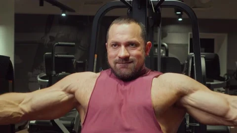 Bodybuilder performs an exercise on the chest muscles on a simulator in the gym Stock Footage 185673637