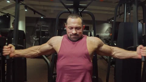 Bodybuilder performs an exercise on the chest muscles on a simulator in the gym Stock Footage 185674030