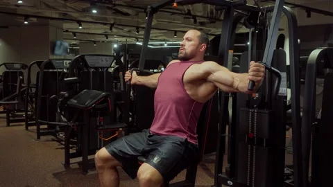 Bodybuilder performs an exercise on the chest muscles on a simulator in the gym Stock Footage 185674366