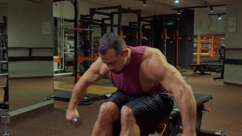 Bodybuilder performs exercise with dumbbells on muscles of the back and triceps Video stock 185631319