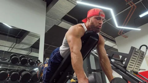 Bodybuilder performs exercise with dumbbells on the triceps and back muscles Video stock 188700203