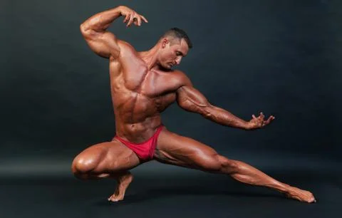 Bodybuilder posing on dark background. Stock Photos