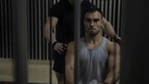 Bodybuilder pulls training machine with lot of weight under control of coach. Stock Footage 85330244