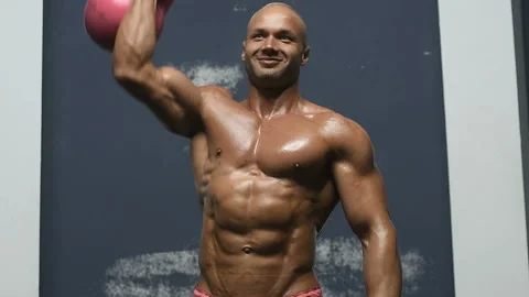 Bodybuilder pumping up muscles with kettlebell Video stock 131385115