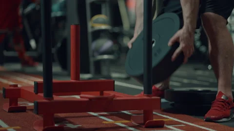 Bodybuilder putting barbell plates on exercise stand in gym Stock Footage 148325290