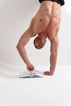 Bodybuilder reads the book on a white background isolated at the bottom of his Foto stock