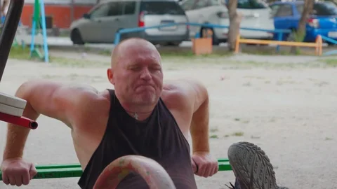 A bodybuilder shakes the press on his simulators in the yard outdoors Stock Footage 114622625