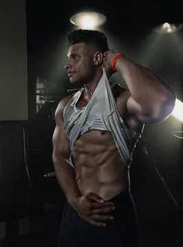 Bodybuilder showing off his abs in the gym holding up his t-shirt, creative Stock Photos