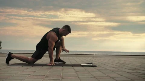 Bodybuilder shows a stretching exercise, training online, through a computer Stock Footage 200118235